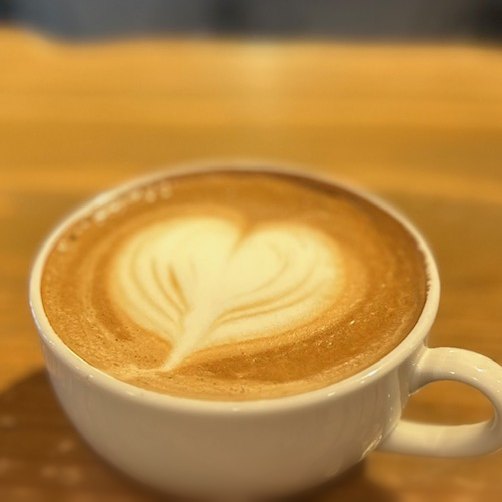 ハートのラテアートを描いた白いカップのカフェラテ